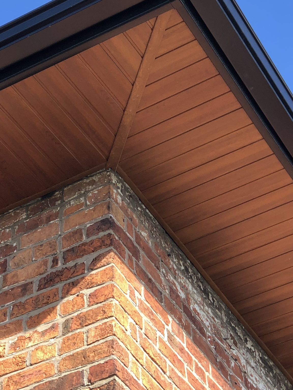 Close-up of light oak soffit and black seamless aluminium gutter